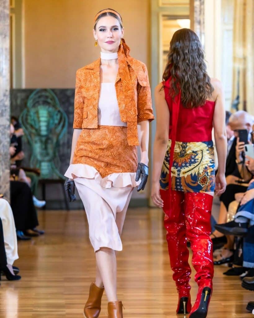 Runway model walking in an orange batik-inspired set at Milano Fashion Official in Milan.