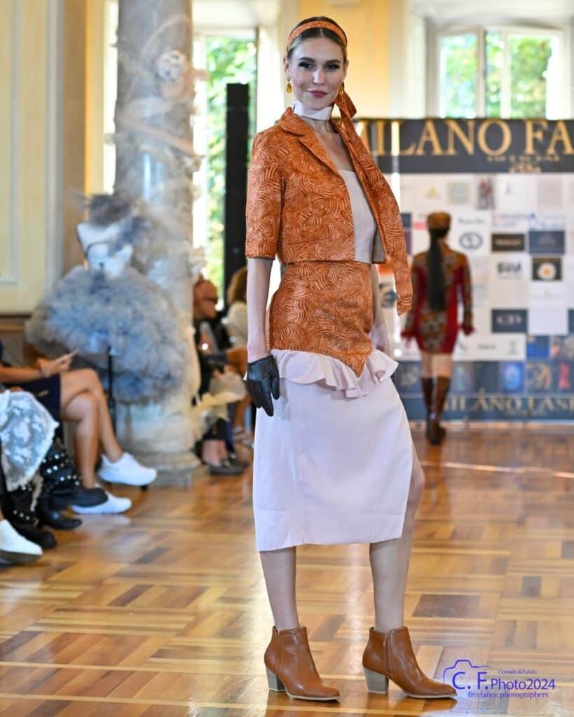Runway model in an orange batik-inspired jacket and skirt look at Milano Fashion Official in Milan.